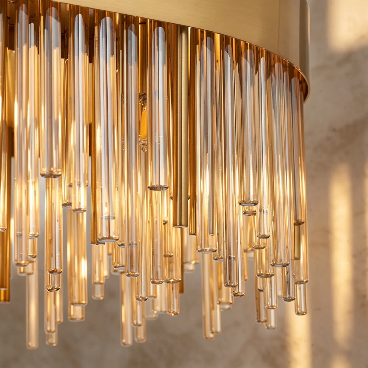 Close up of a gold and glass chandelier with multiple glass tubes hanging down
