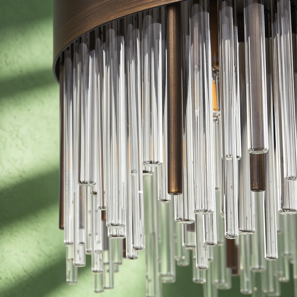 Close up of a chandelier with clear glass rods and bronze metal accents