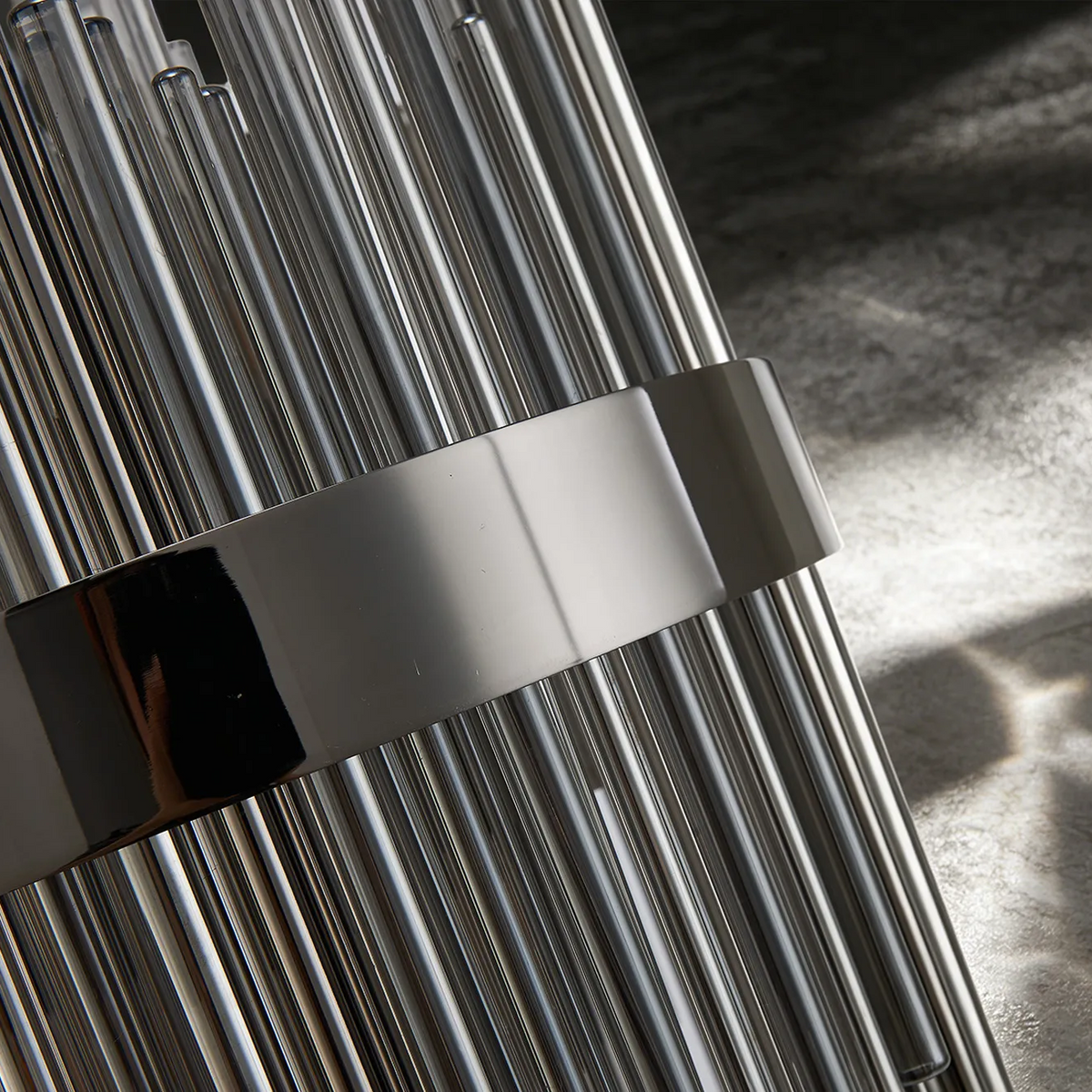 Close up of a modern light fixture with clear glass rods and a polished chrome band