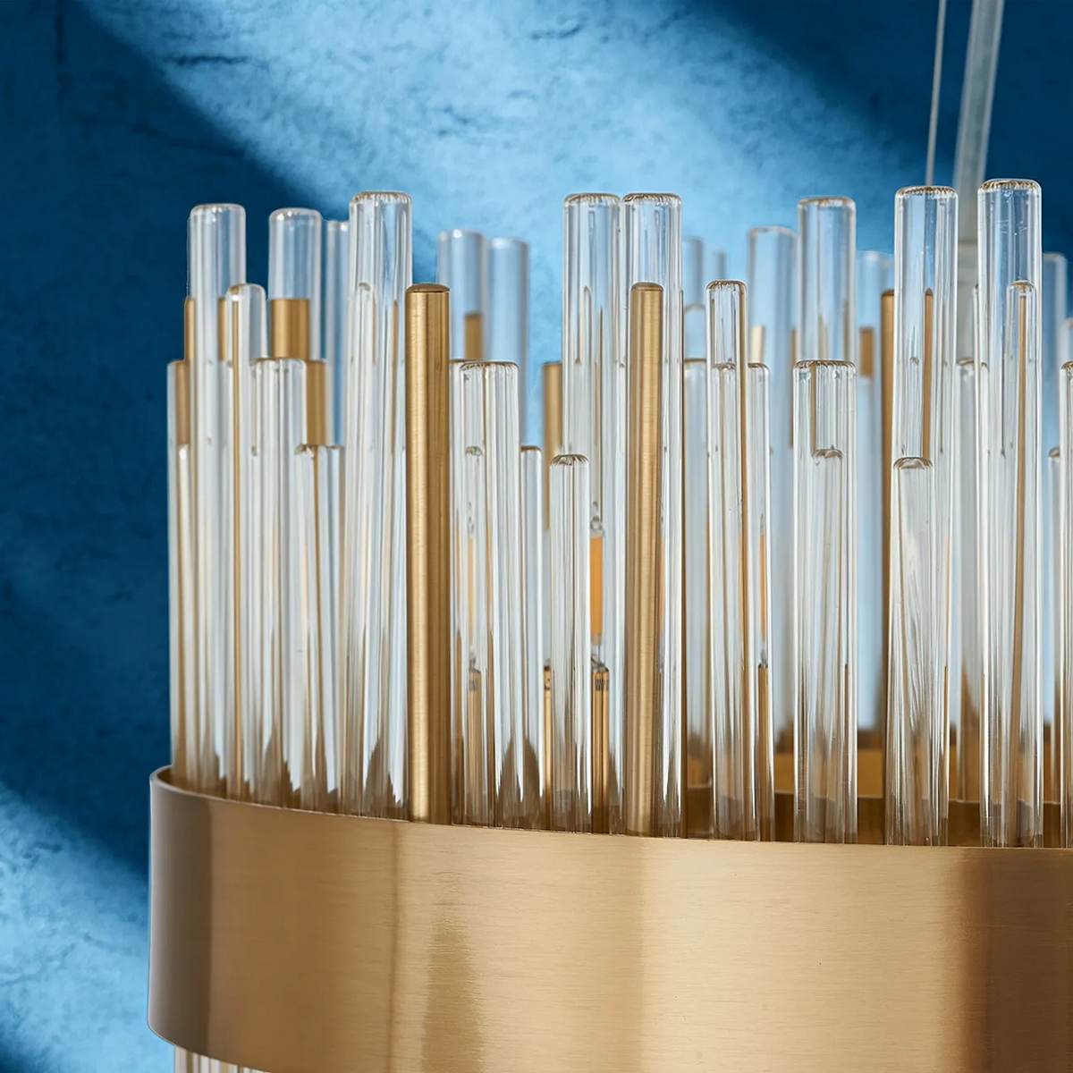 Close up of a gold chandelier with many glass rods and a gold band