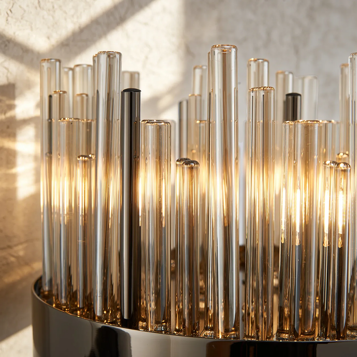 Close up of a modern chandelier with multiple amber glass tubes and a polished metal base
