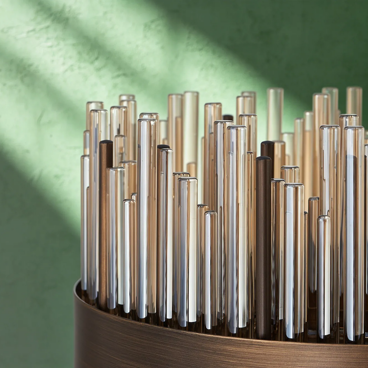Close up of a lamp with many glass tubes in varying heights and colors, set in a bronze base