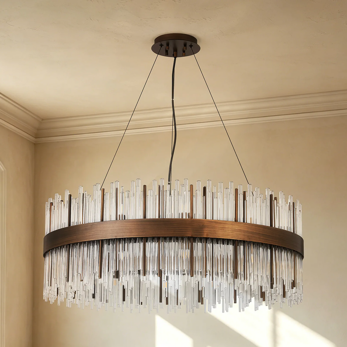 Round chandelier with a bronze frame and clear glass rods hanging at varying lengths