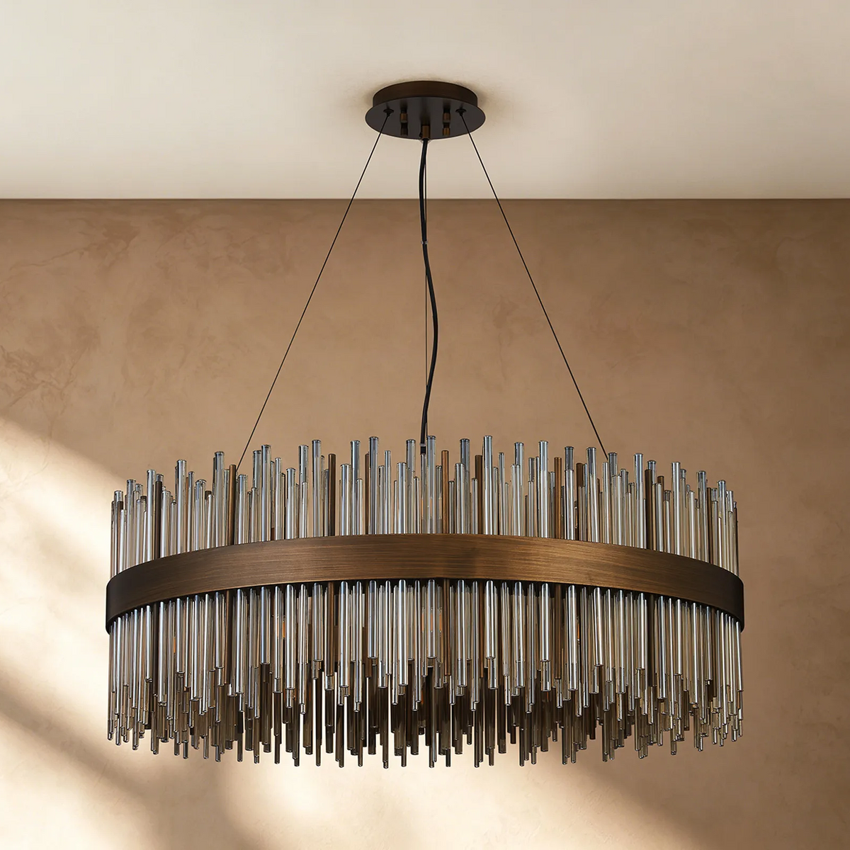 Round chandelier with bronze frame and clear glass rods hanging from a ceiling
