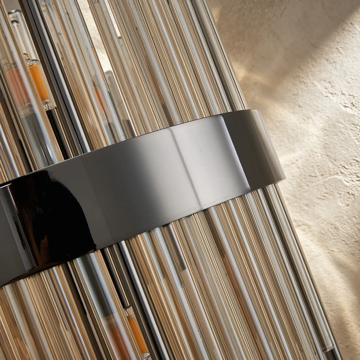 Close up of a black metal band around vertical glass rods, with a textured beige background