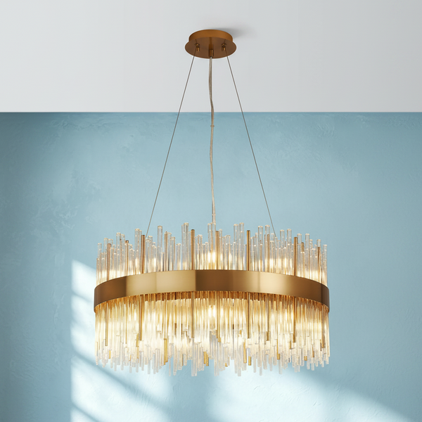 Round gold chandelier with clear glass rods hanging from a white ceiling against a blue wall