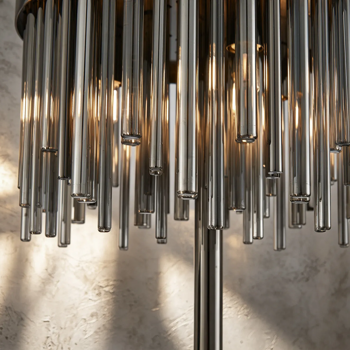 Close up of a chandelier with multiple glass rods hanging down, with light shining through them