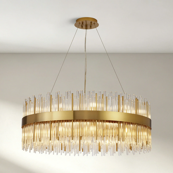 Round gold chandelier with clear and gold glass rods hanging from a white ceiling