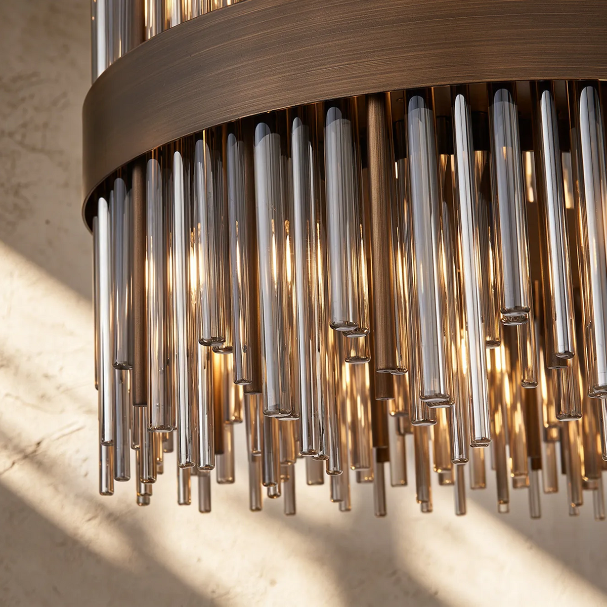Close up of a bronze chandelier with many glass rods hanging down, illuminated from within