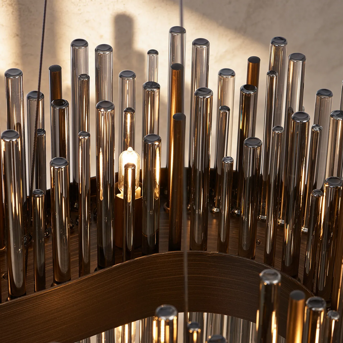 Close up of a chandelier with many glass and metal rods of varying heights and a light bulb in the center