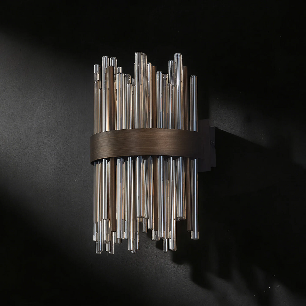 Wall sconce with clear and amber glass rods in a bronze metal band