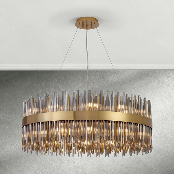 A gold and glass chandelier hangs from a white ceiling, illuminating a textured gray wall below