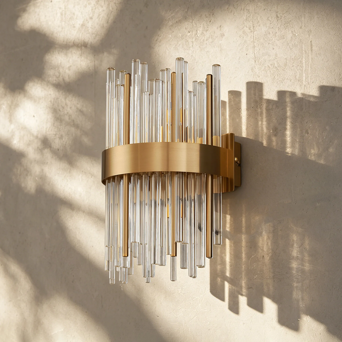 Wall-mounted light fixture with a brass band and clear and gold glass rods