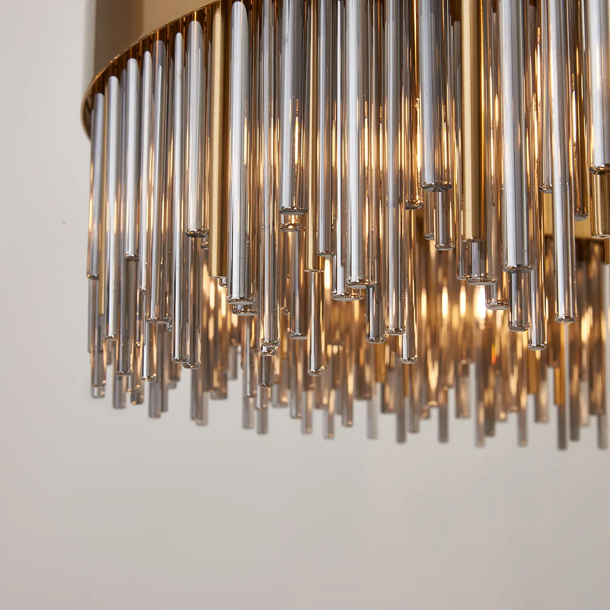 Close up of a chandelier with many glass rods hanging down, illuminated from within