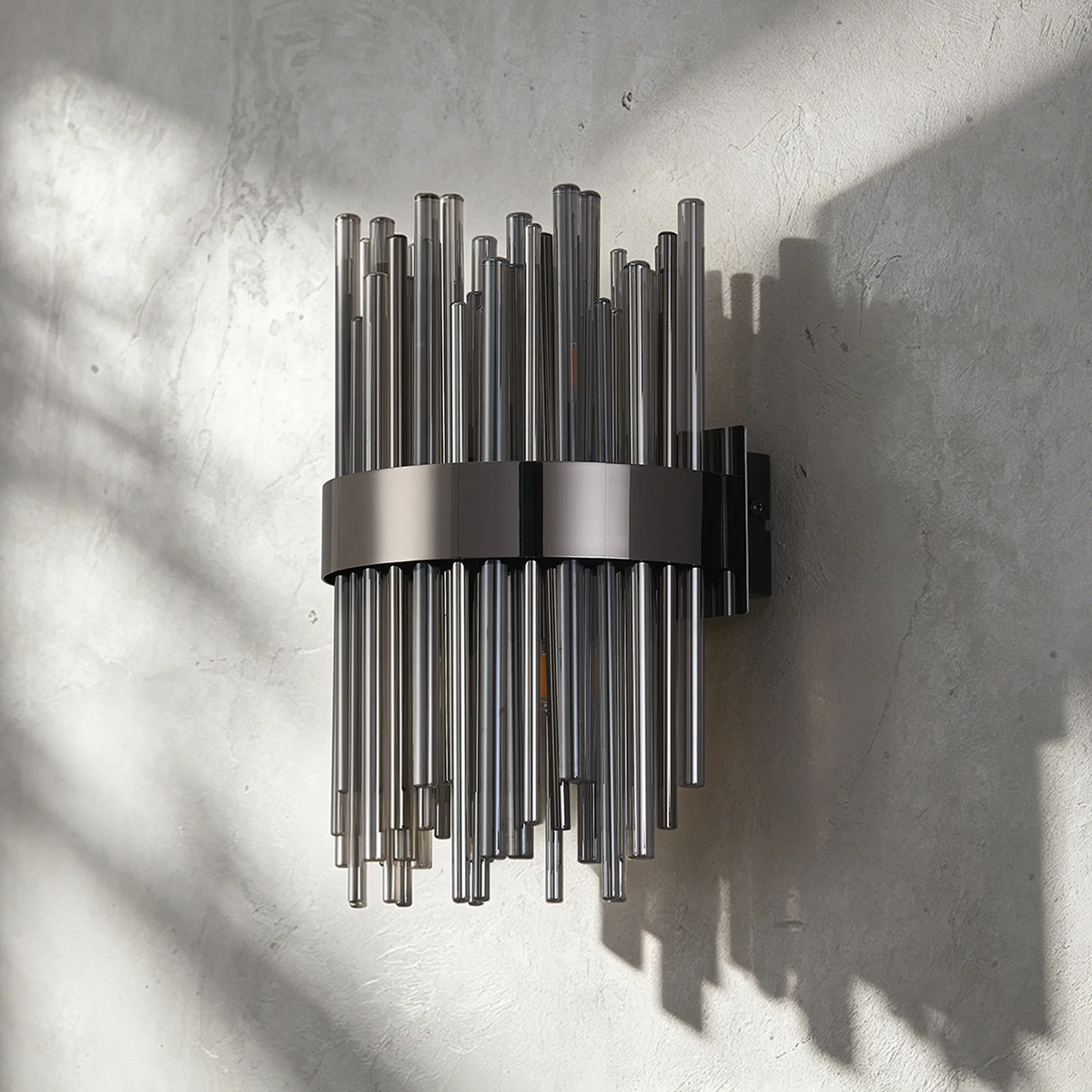 Wall sconce with vertical glass rods in varying lengths, held by a horizontal metal band