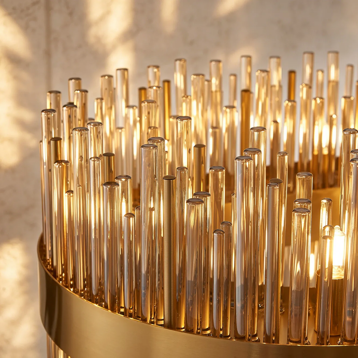 Close up of a gold chandelier with many glass rods and a light bulb