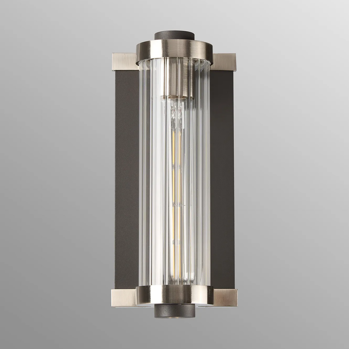 Vertical wall sconce with a dark bronze backplate and brushed nickel accents, clear ribbed glass cylinder