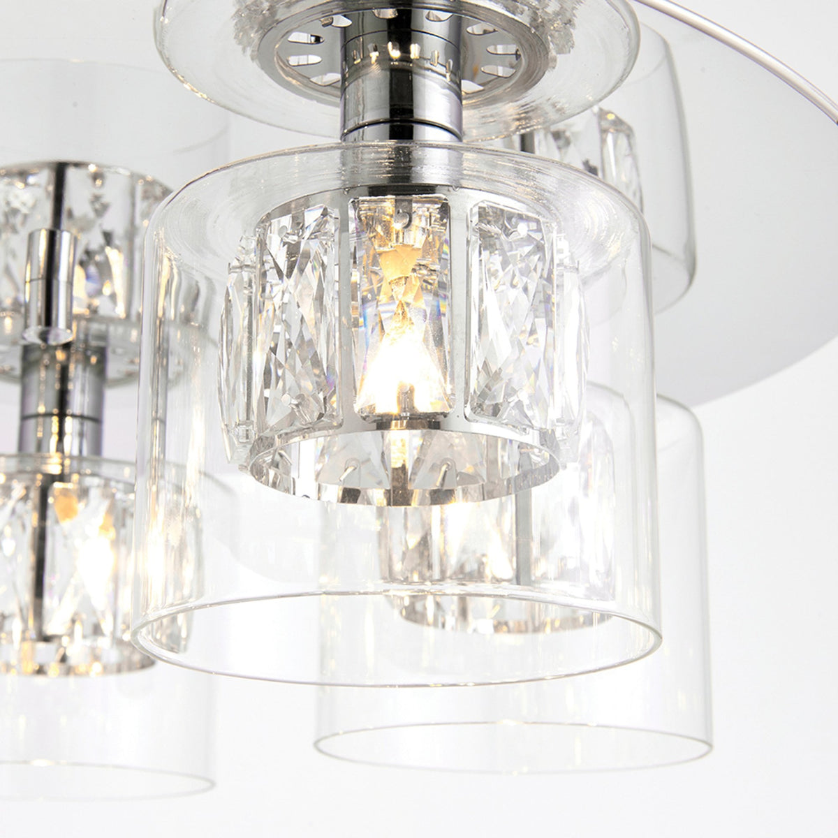 A close-up of one of the clear glass shades on the chrome and crystal ceiling light.