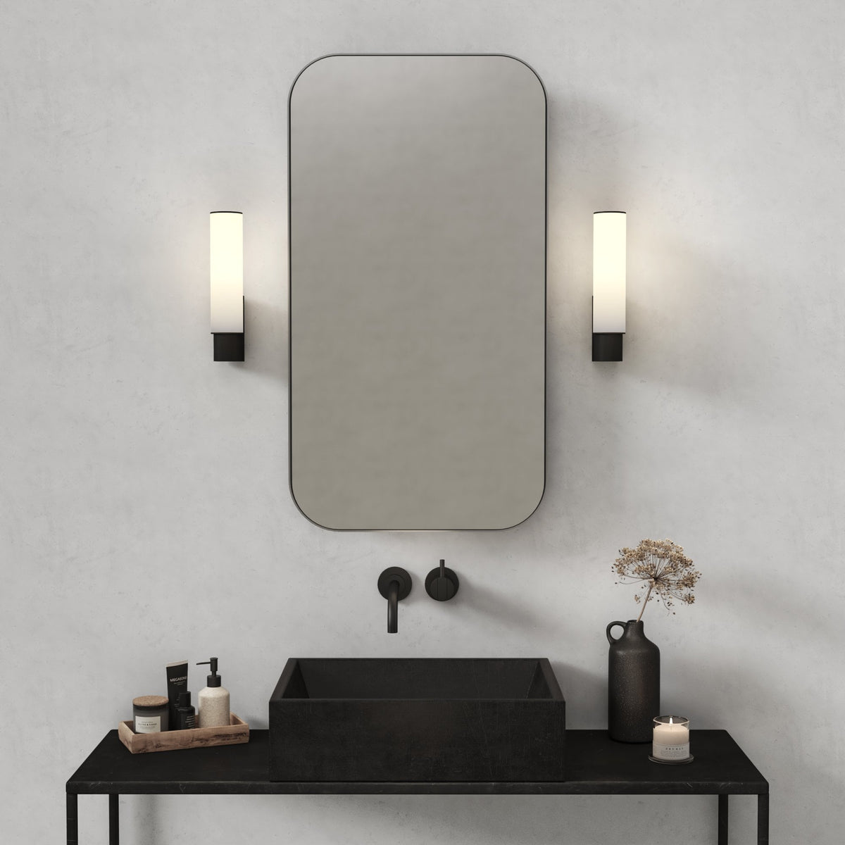 Bathroom vanity with black sink, mirror, wall-mounted faucet, and two vertical wall sconces