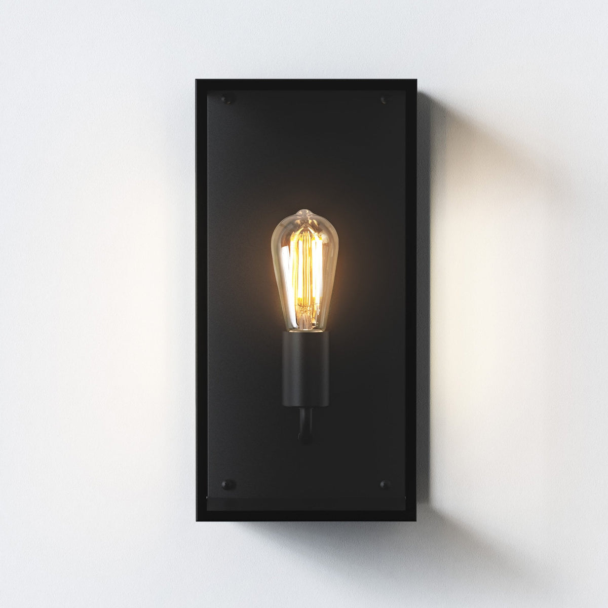 Black rectangular wall sconce with an exposed, glowing Edison bulb