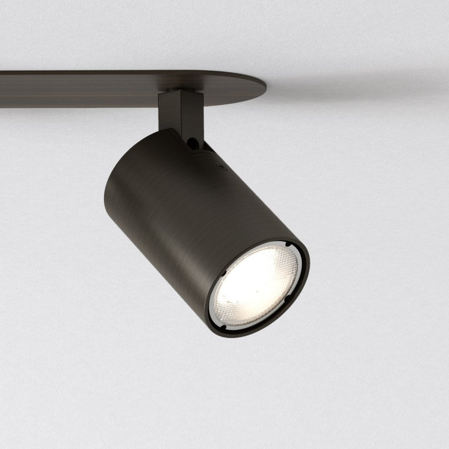 Dark bronze cylindrical ceiling spotlight with a bright bulb