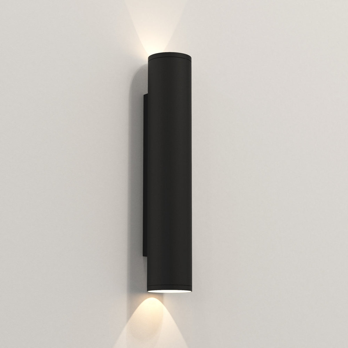 Black cylindrical outdoor wall light with light shining upwards and downwards