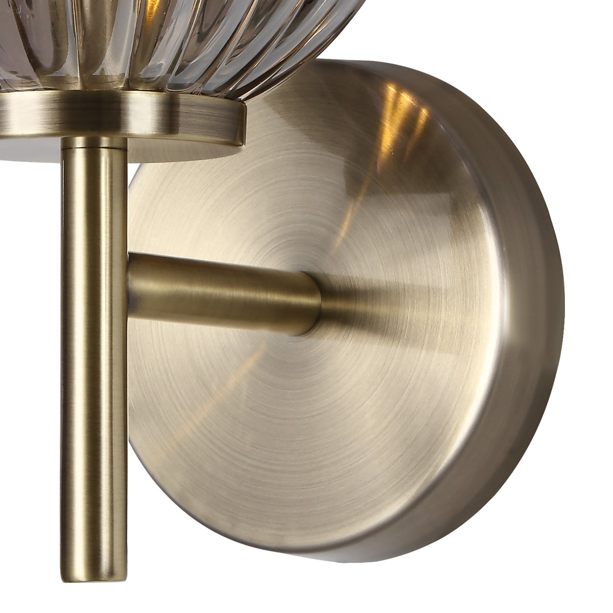 Close-up of the antique brass wall plate of the ribbed smoked glass wall light.