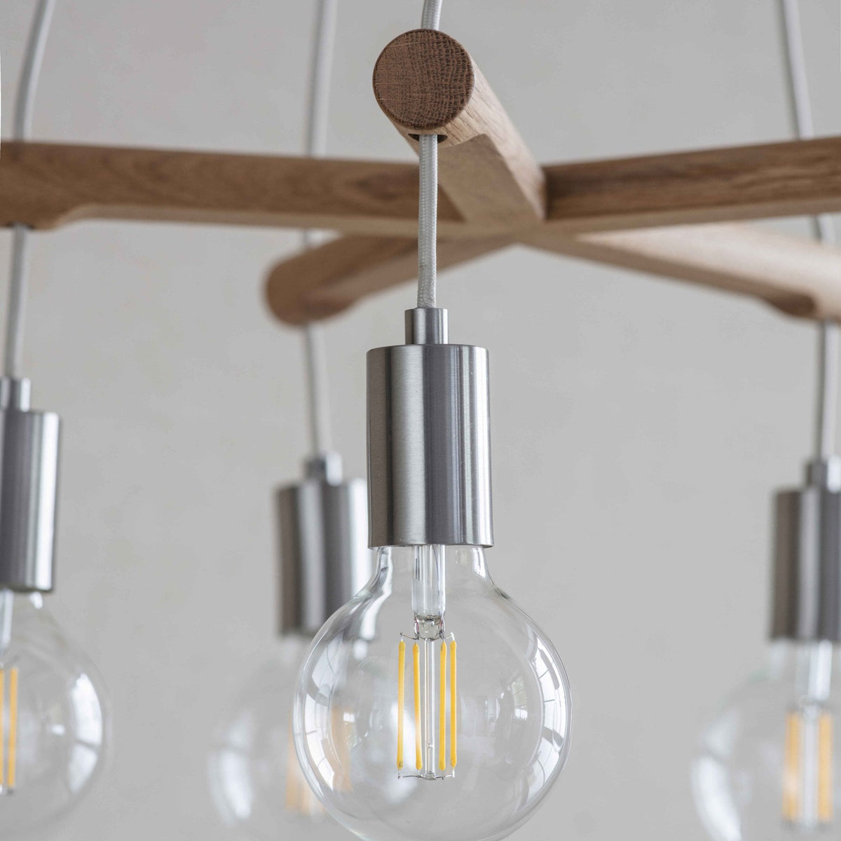 Close-up of a modern chandelier with exposed LED bulbs and a wooden frame.
