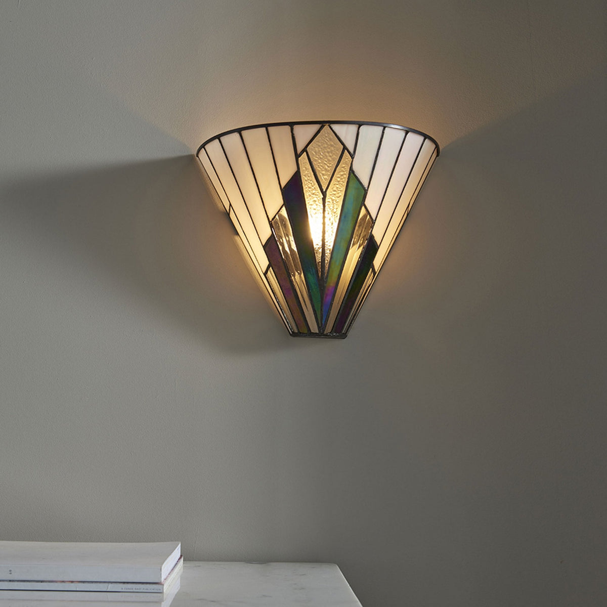 Art Deco style wall light on a grey wall, illuminating the space with a warm glow.