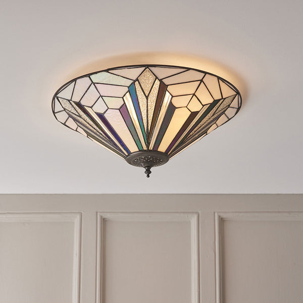 A close up of a tiffany style ceiling flush light with an art deco pattern.