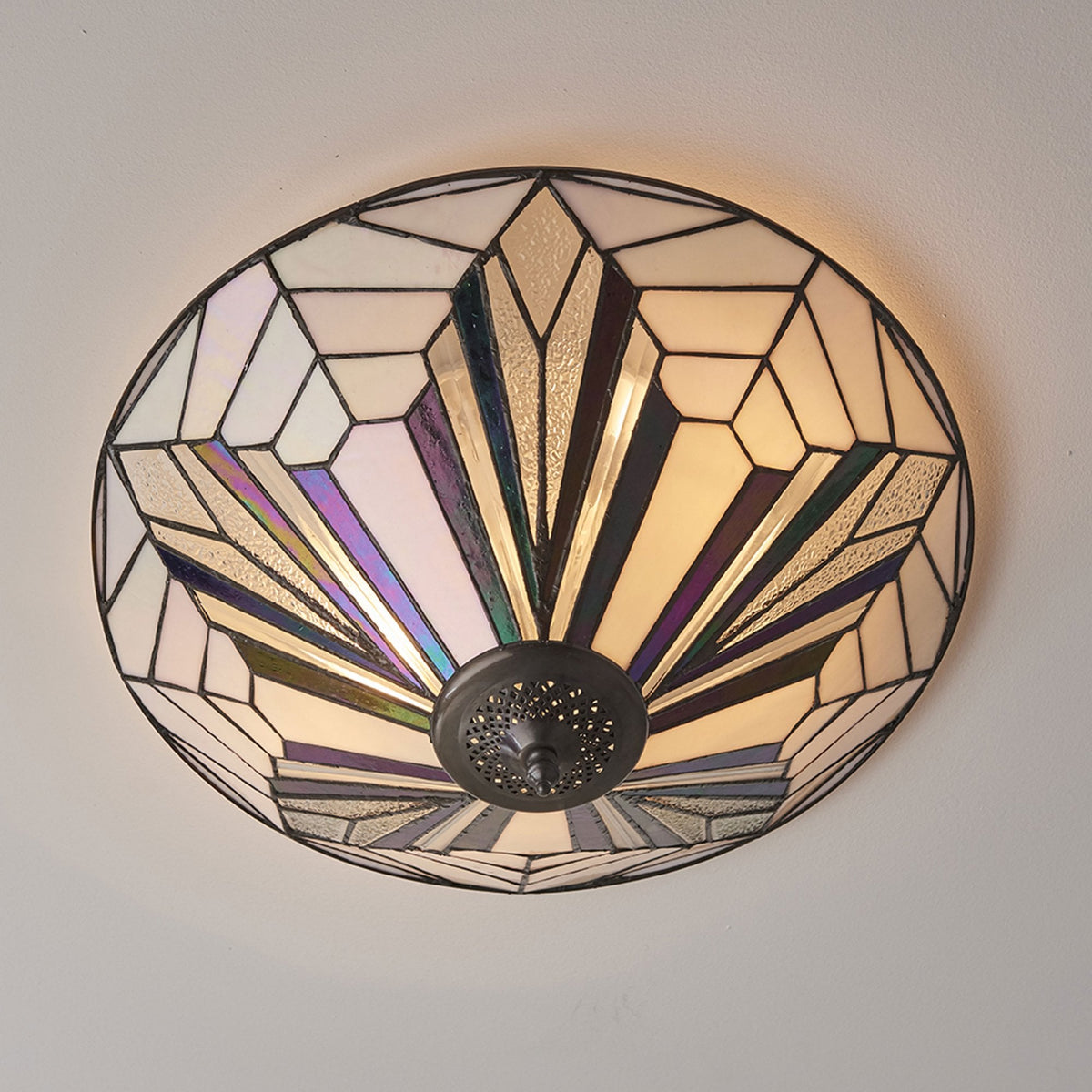 A close up of a tiffany style ceiling flush light with an art deco pattern.