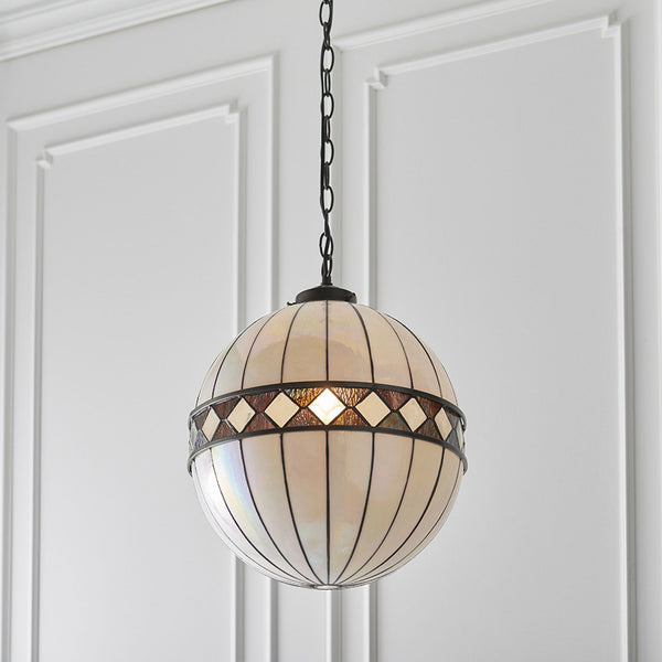 A close-up of a white and brown stained glass globe pendant light hanging from a ceiling.