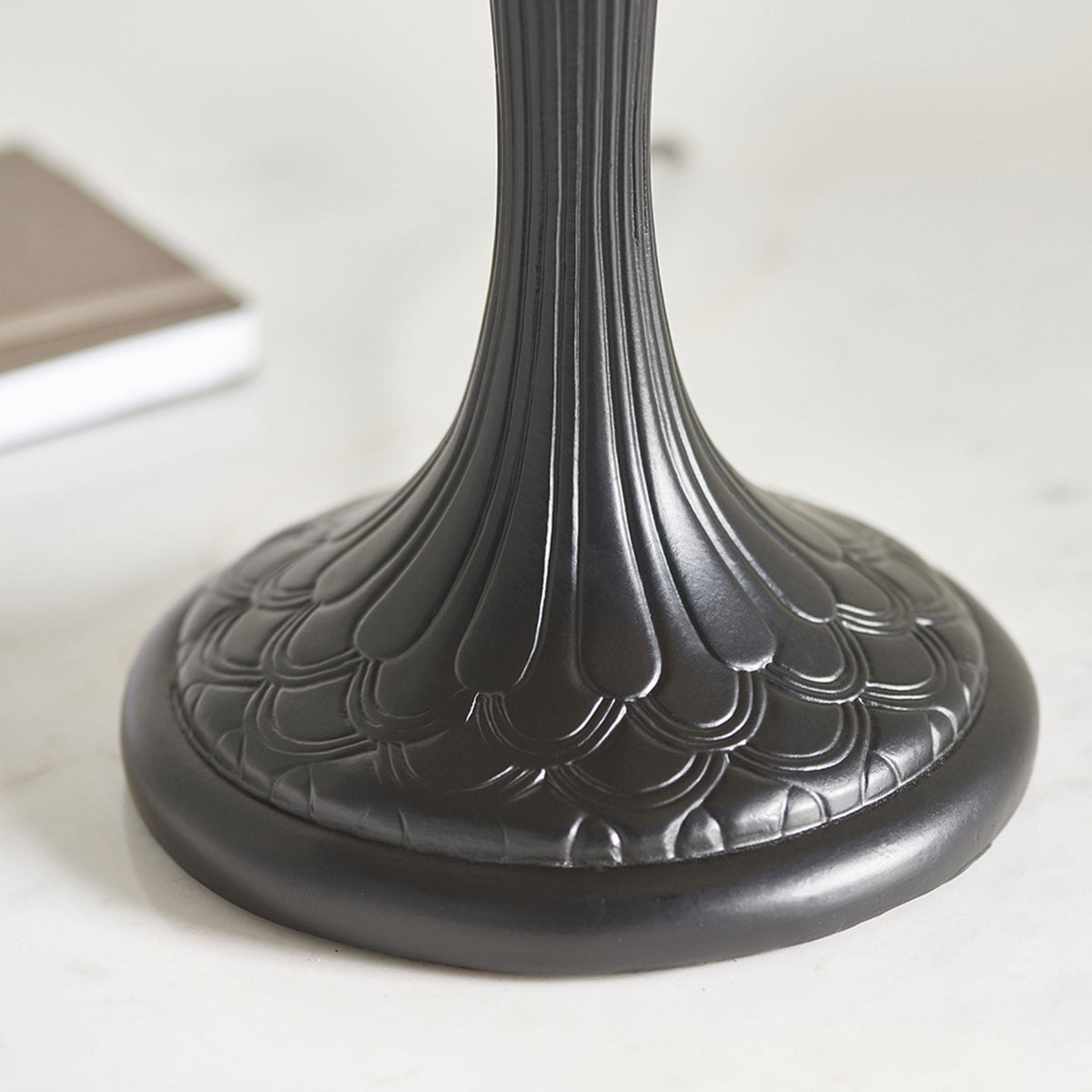 Close-up of the lamp's sturdy, dark bronze base with intricate feather-like detailing.