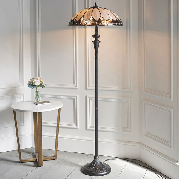 A Tiffany-style floor lamp with a stained-glass shade, next to a small white side table.