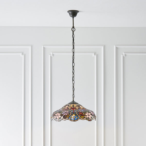 A Tiffany-style pendant light with a floral stained-glass shade hanging in a room.