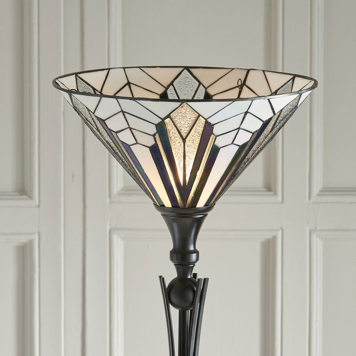 Close-up of a decorative floor lamp with a geometric stained-glass shade. A period.
