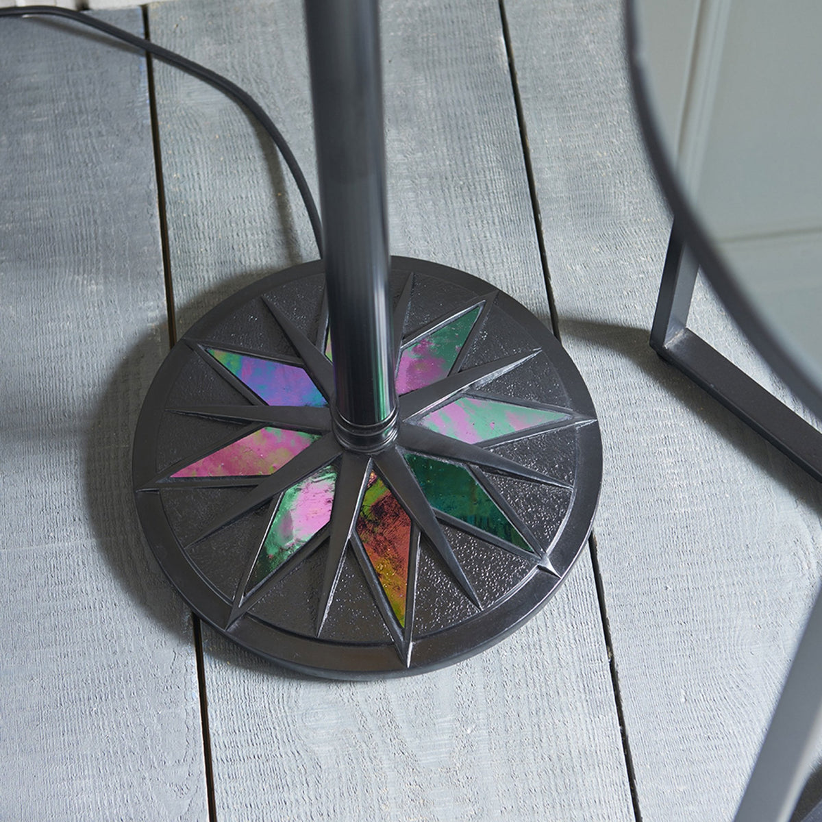 Close-up of the round base of a floor lamp with colourful stained-glass inserts. A period.
