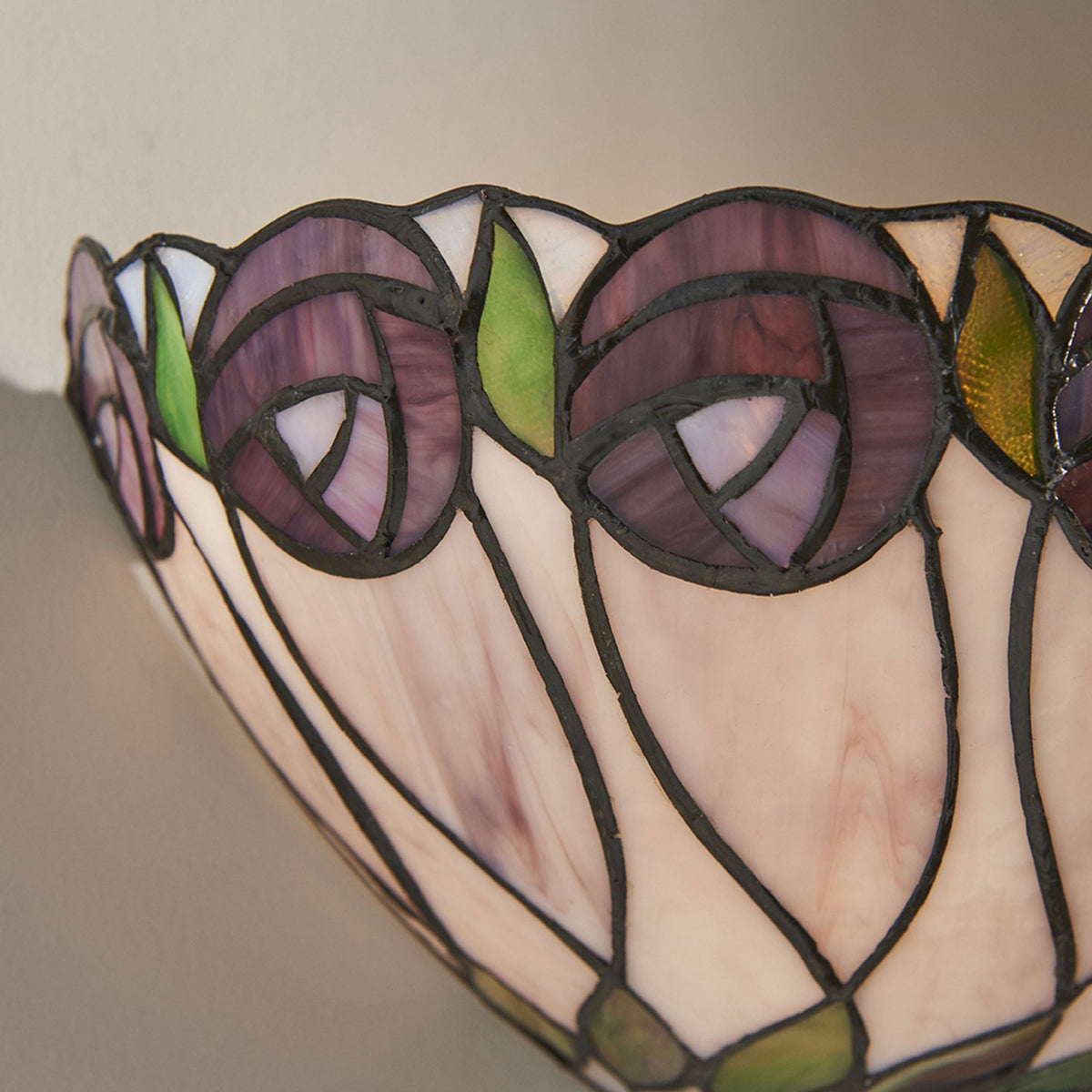 A close-up of a Tiffany wall light with a purple stained glass flower pattern.
