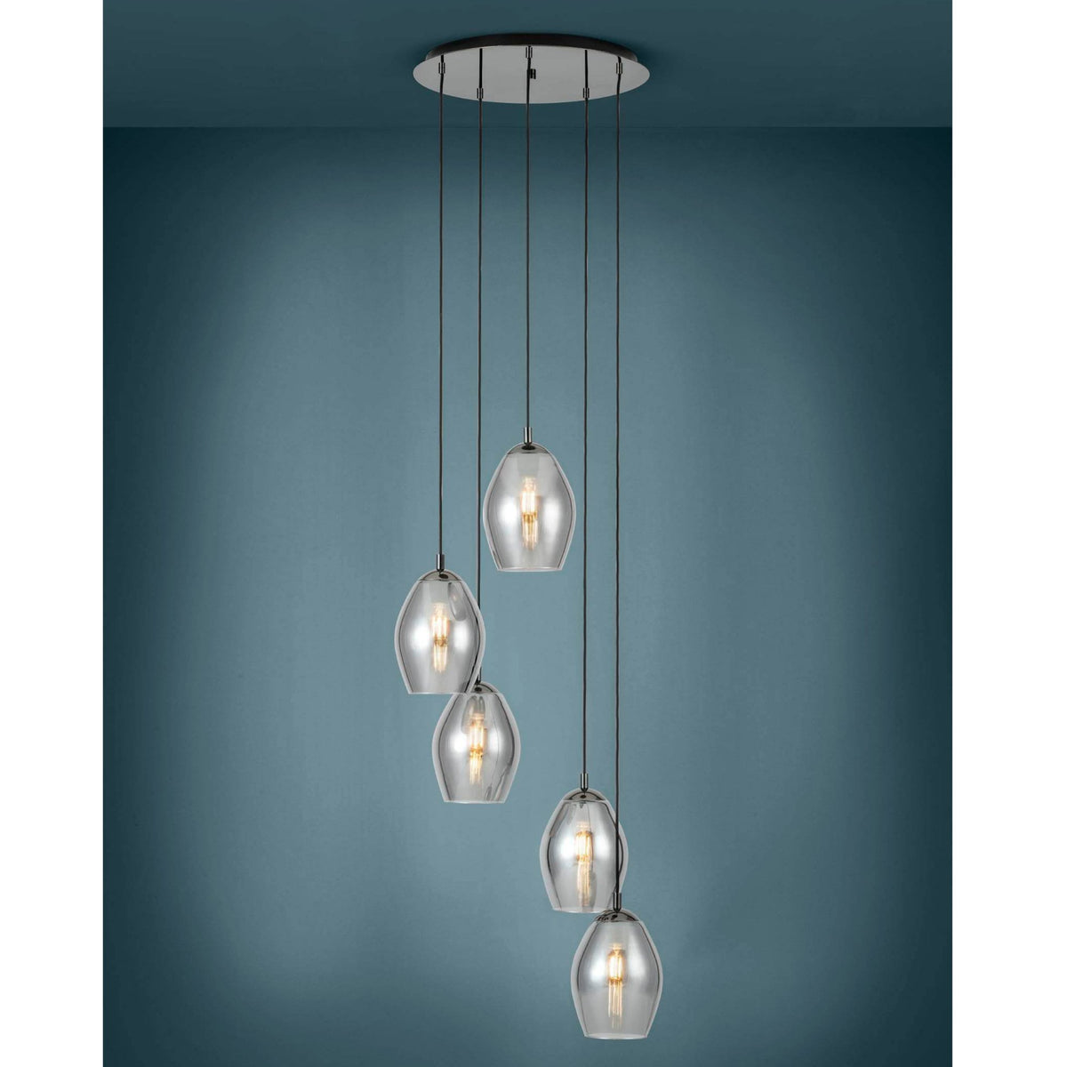 Five clear glass pendant lights with exposed bulbs hang from a circular ceiling fixture against a blue wall.