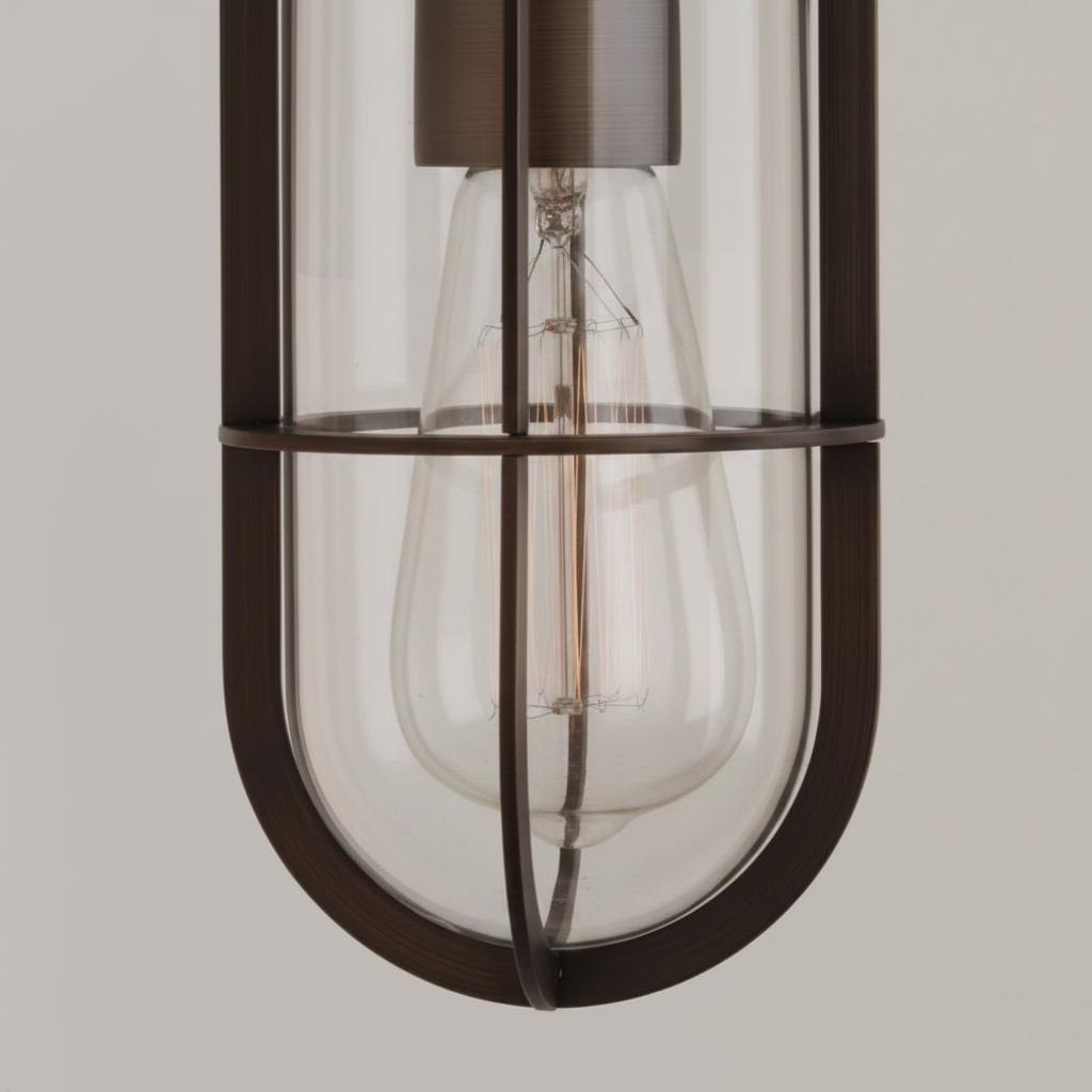 Close up of a bronze pendant light with a clear glass shade and exposed filament bulb