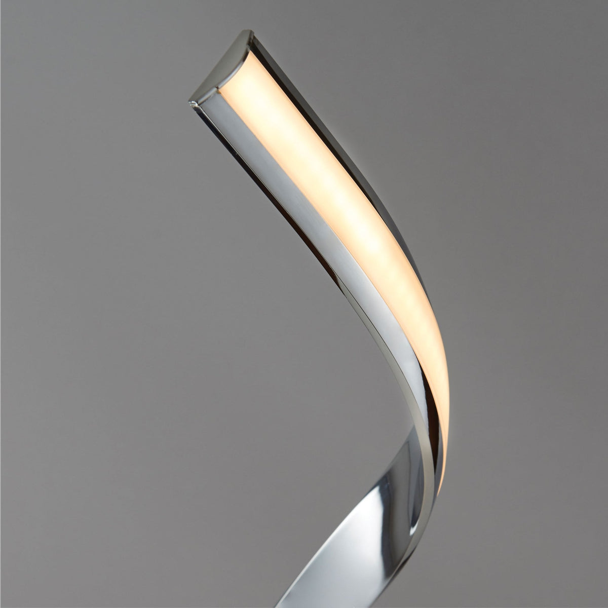 Detail of the illuminated LED strip on the chrome spiral floor lamp against a gray background.