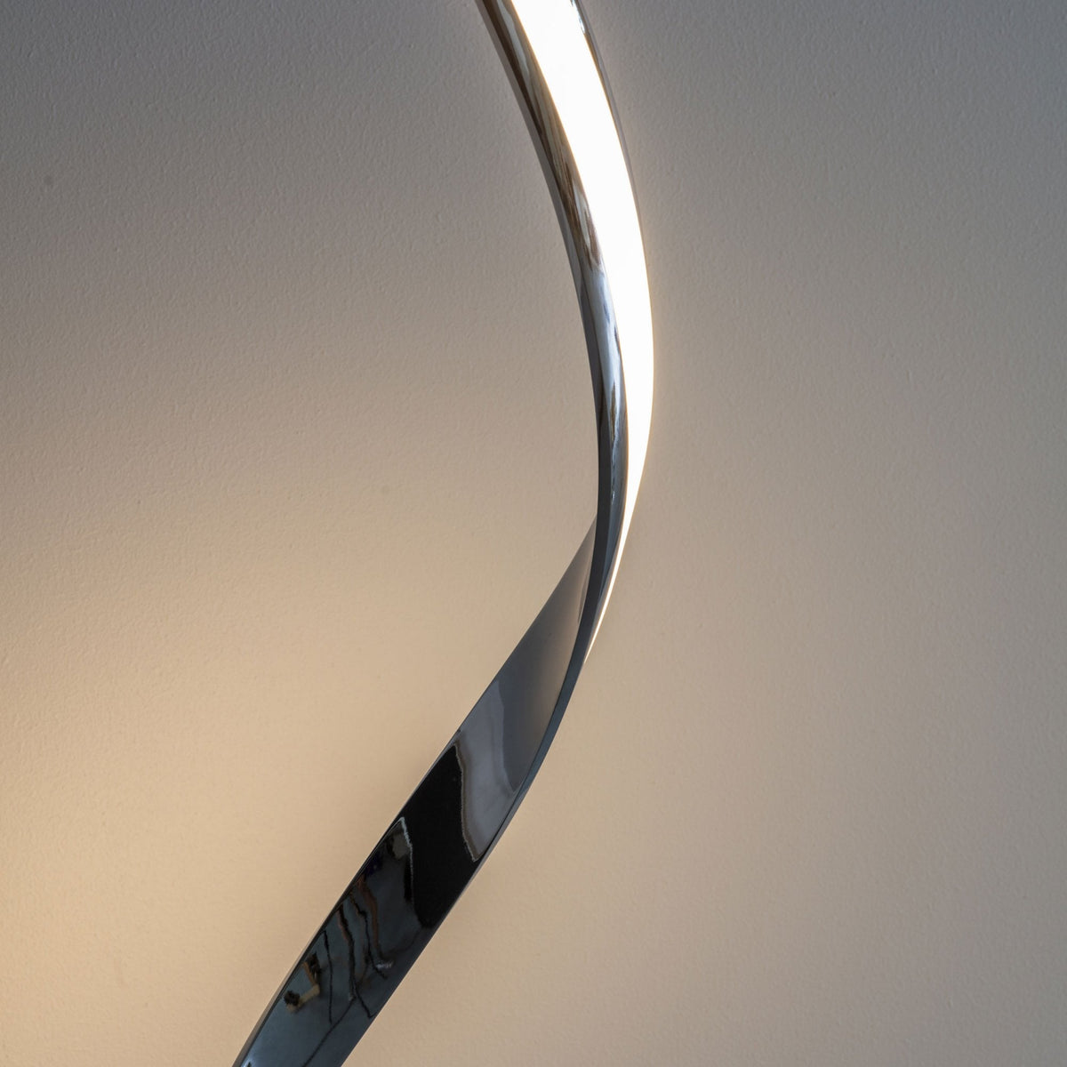 Close-up of the chrome spiral design of an LED floor lamp, showing its sleek curve.