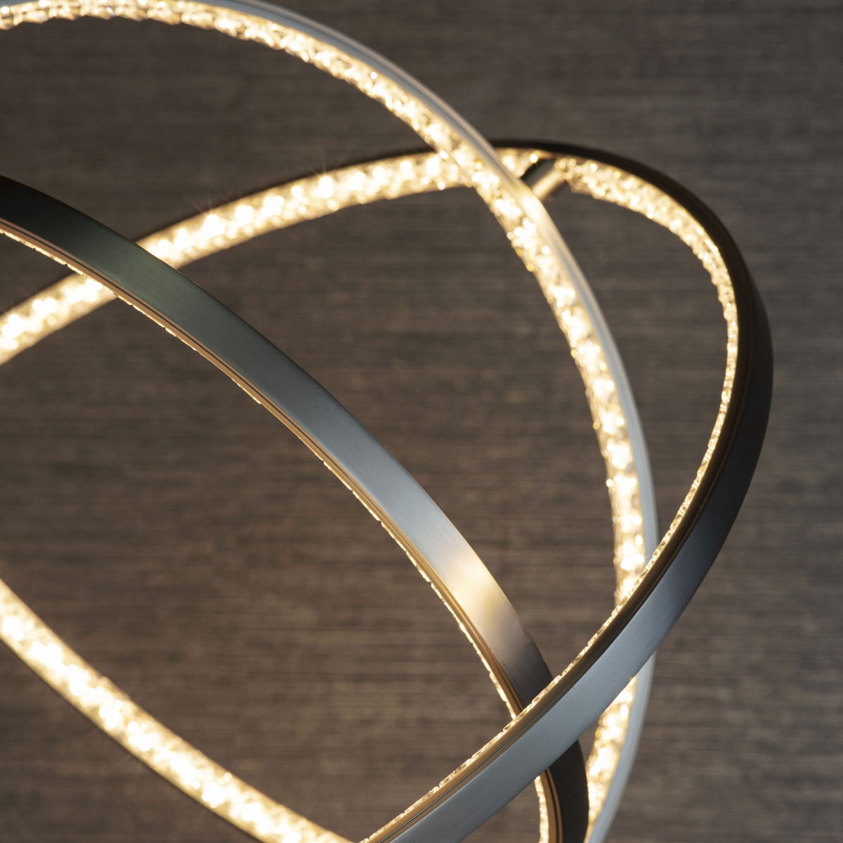 A close-up view of a modern pendant light with intersecting illuminated rings.