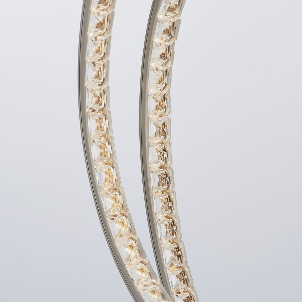 Close-up of the two intertwined rings, showcasing the intricate crystal detailing within the illuminated sections.