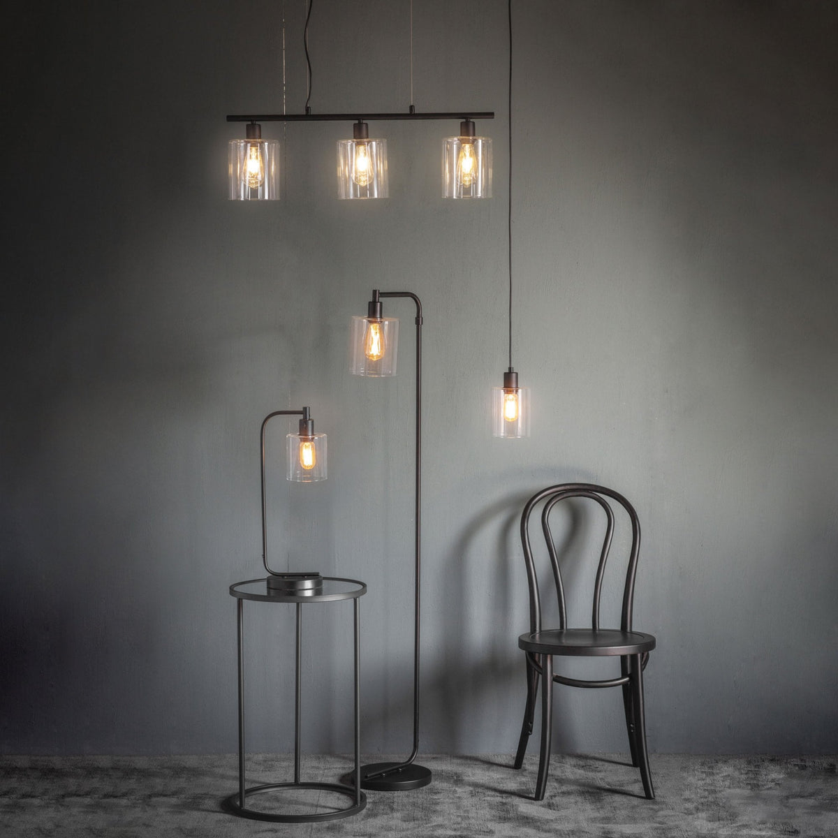 Collection of industrial-style lighting: a three-light pendant, a floor lamp, a table lamp, and a single pendant.