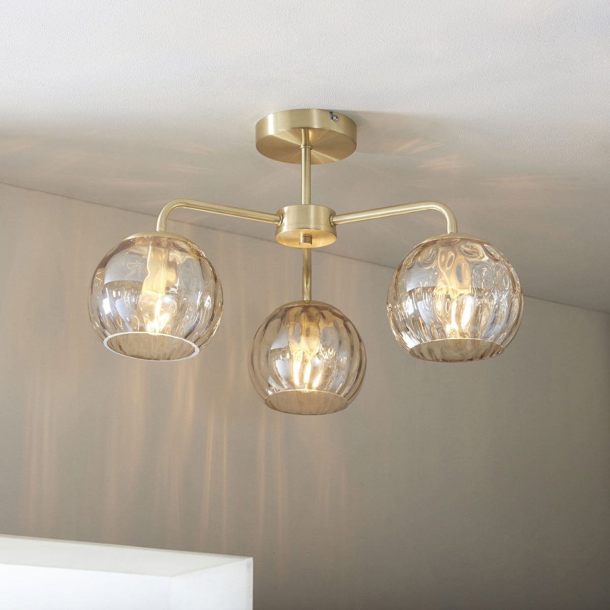 Three-light ceiling fitting with clear glass shades and a brass finish.