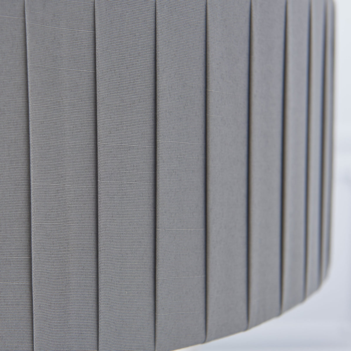 Close-up of the grey pleated fabric of a drum lampshade.