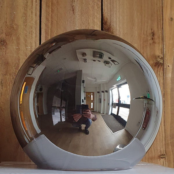 A large smoked glass globe table lamp on a wooden background, showing a reflection.