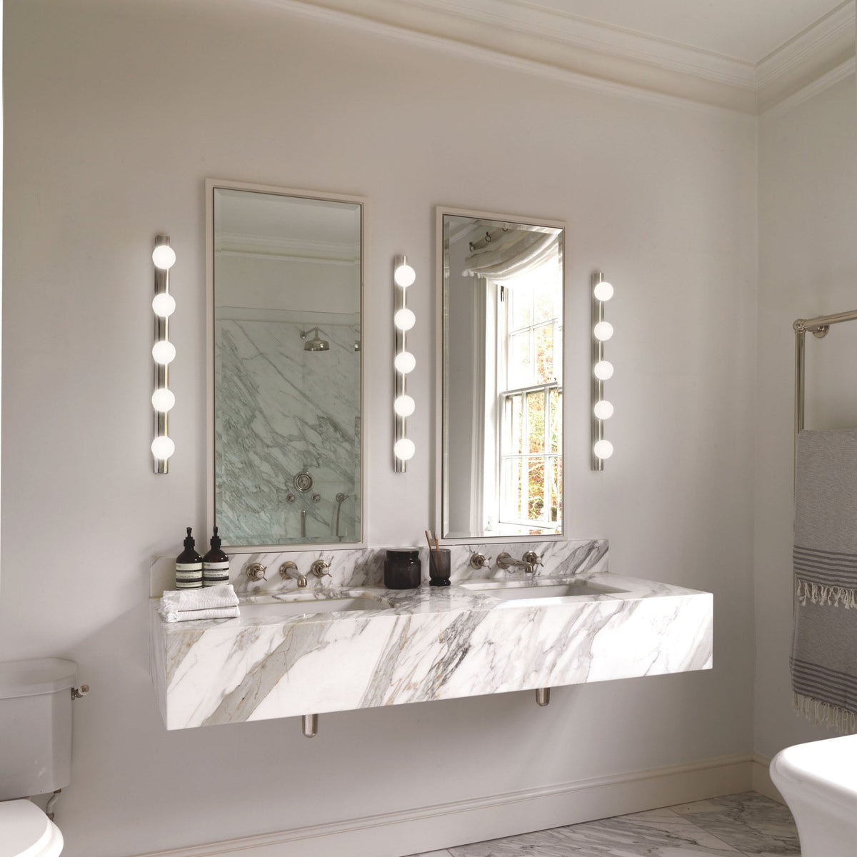 Modern white marble bathroom with two mirrors and vanity lights.