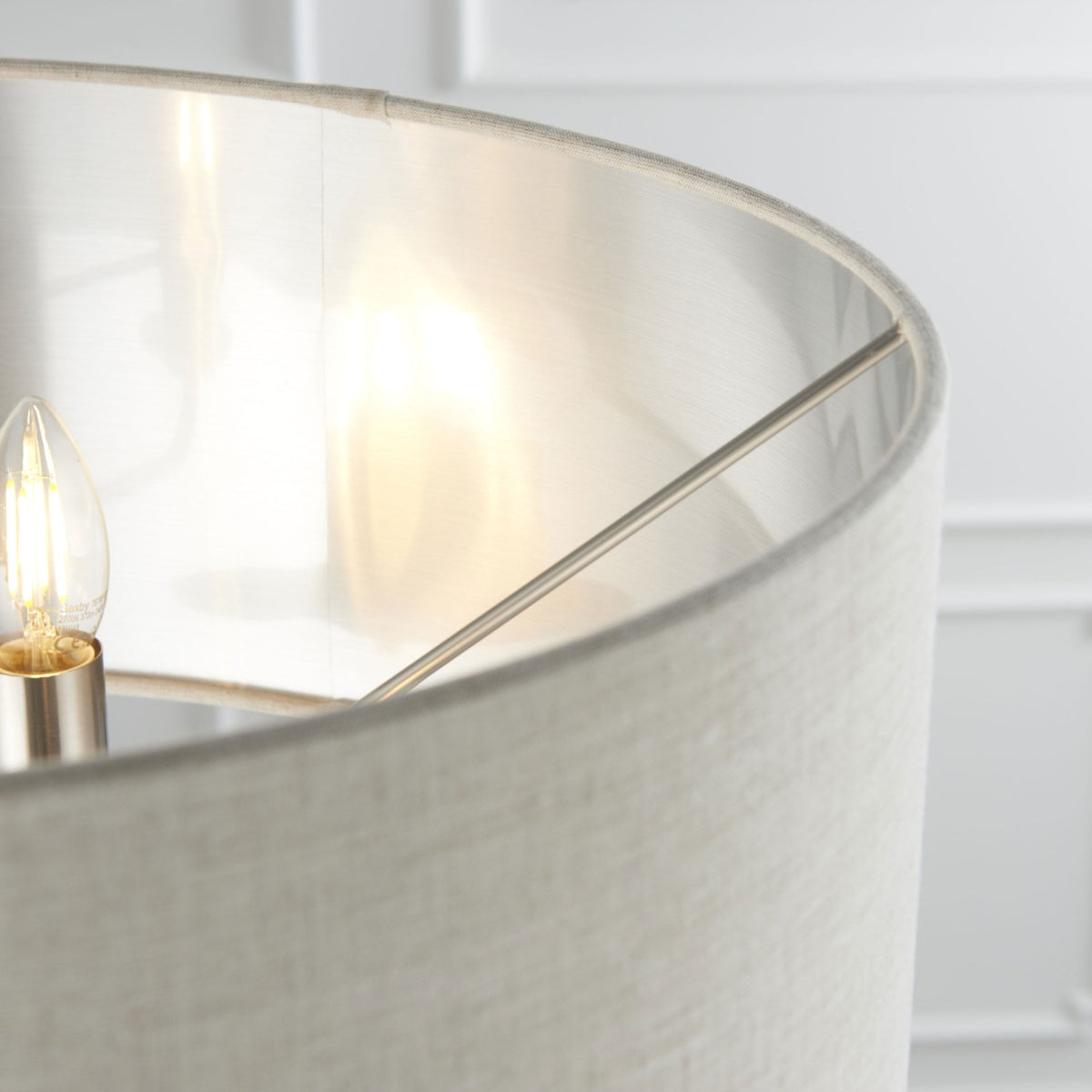Close-up of the interior of a floor lamp shade, showing a lit bulb and brushed nickel accents.